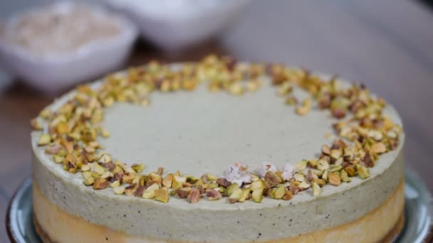 Manos femeninas decorando pastel de queso pistacho en la cocina . — Vídeos de Stock