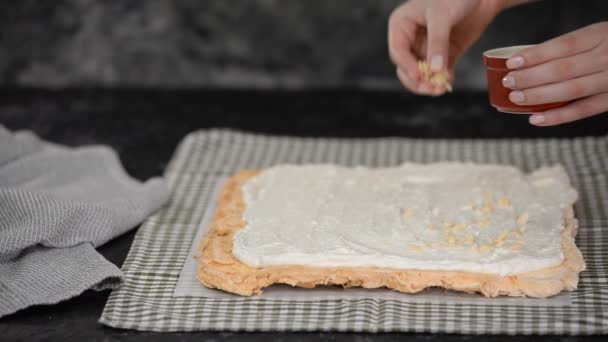 Banketbakker maakt een meringue roll cake, strooi amandelen op de meringue basis. — Stockvideo