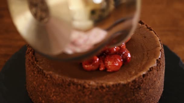 Kvinna dekorerar choklad cheesecake med körsbärssås. — Stockvideo