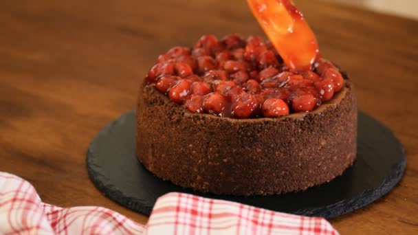 Woman decorates chocolate cheesecake with cherry sauce. — Stock Video