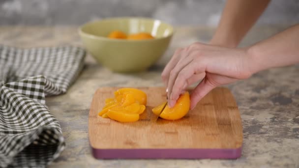 Cortar el melocotón enlatado en una tabla de cortar de madera . — Vídeos de Stock