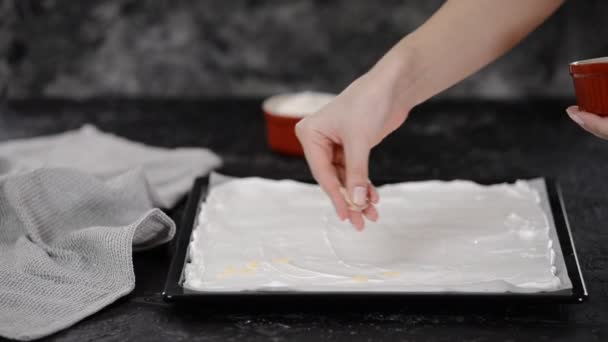 Pasticcere fa una torta di meringa roll, cospargere scaglie di mandorle sulla base di meringa . — Video Stock
