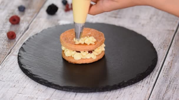 Pastelero haciendo francés Mille Feuille con natillas y bayas. Millefeuille postre francés de hojaldre y crema de natillas . — Vídeos de Stock