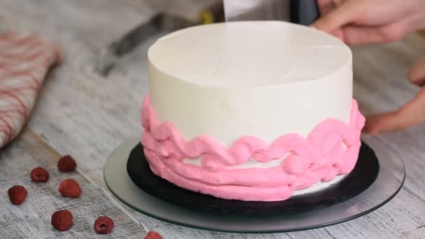 Женщина намазывает крем для глазури на слой торта . — стоковое видео