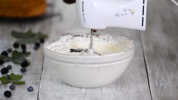 Banketbakker voegt bessenpuree toe aan boterroom. Klop met een mixer bessen crème. — Stockvideo