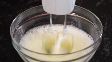 Elleri yumurta beyazı kremalı ve karıştırıcılı. Yumurta beyazıyla kaseye şeker ekle