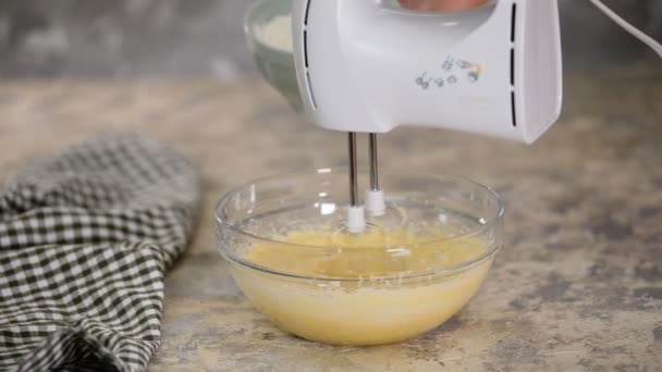 Adicionando farinha para massa em tigela de vidro. Mistura de massa de bolo com misturador . — Vídeo de Stock