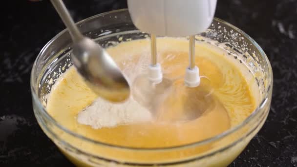 Ruce smíchejte těsto ve skleněné misce se mixérem. Přidávání mouky do misky s těstem. — Stock video