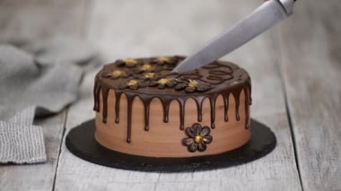 Şekerci elleri çiçeklerle süslenmiş çikolatalı pasta ile kesilmiş..