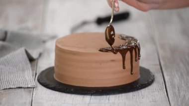 Erimiş çikolatayla çikolatalı pasta. Pastanın üstüne çikolata döken kadın. Ev yapımı kakaolu kek..