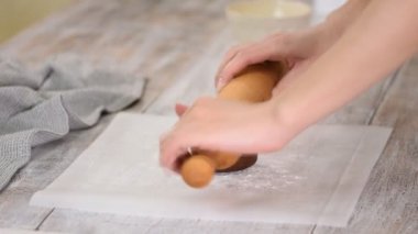 Kadın eli merdaneyle çikolata hamuru yuvarlıyor. Ev yapımı çikolatalı pasta..