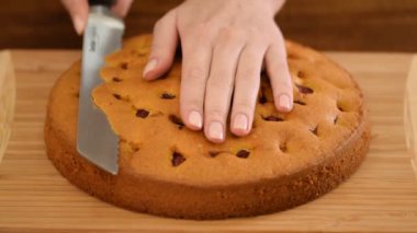 Kadın eli kirazlı sünger kekinin tepesini kesiyor..