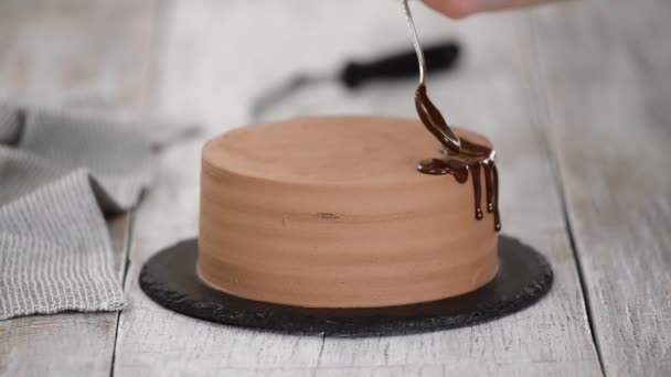 用融化的巧克力磨碎巧克力蛋糕. 女人把巧克力倒在蛋糕上 自制可可分层蛋糕. — 图库视频影像