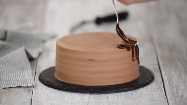 Glazuur chocoladetaart met gesmolten chocolade. Vrouw giet chocolade over taart. Zelfgemaakte cacao gelaagde cake. — Stockvideo