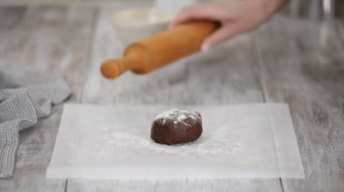 Kadın eli merdaneyle çikolata hamuru yuvarlıyor. Ev yapımı çikolatalı pasta..