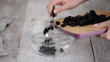 Kadın elleri kurutulmuş kuru eriği bir kaseye koydu. Sağlıklı yeme kavramı.