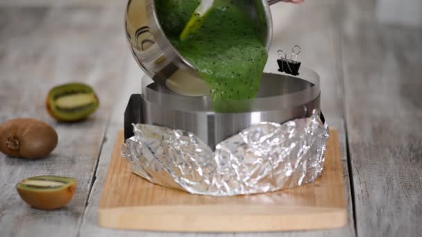 Chef de pastelaria fazendo um bolo de mousse kiwi na cozinha. Despejando geléia kiwi em cima do bolo . — Vídeo de Stock