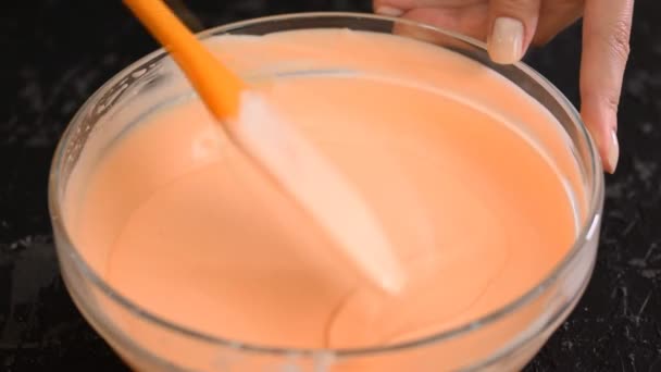 Les mains féminines agitent la mousse orange avec une spatule . — Video