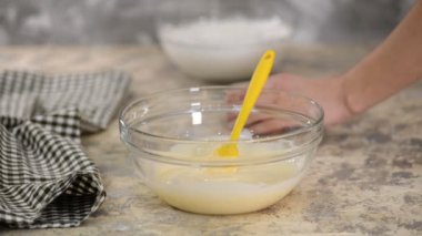 Krem karışımlı bir kaseye jelatin ekleyen kadın.