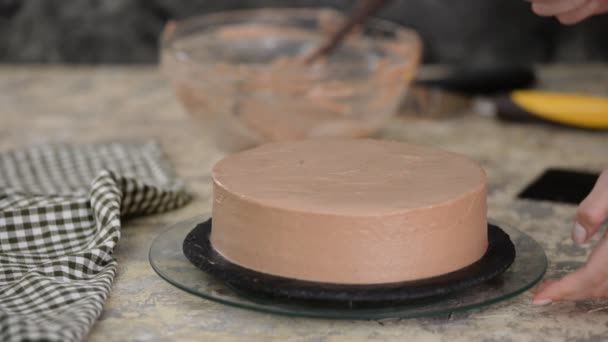 Banketbakker versiert de taart met chocolade room. — Stockvideo