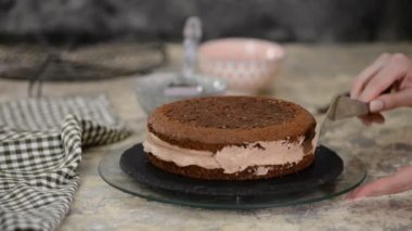 Baker tek katmanlı çikolatalı pastanın kenarlarına buzlu şeker döker..