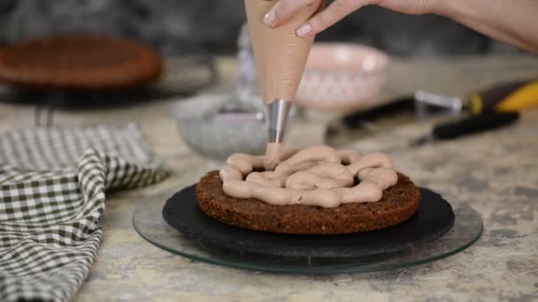 Σεφ ζαχαροπλαστικής κάνει μια τούρτα στην κουζίνα. Γυναικεία χέρια σφίγγει την κρέμα σοκολάτας. — Αρχείο Βίντεο