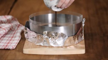 Pasta şefi kremalı kekin üzerine sıvı çikolata döküyor..