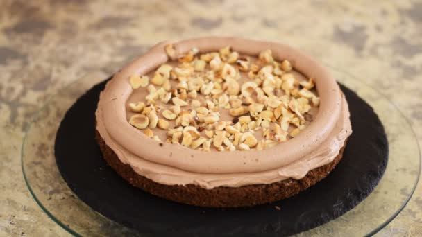 Chef de pastelaria é polvilhe com avelãs no bolo de esponja de chocolate. Fazendo bolo com nozes . — Vídeo de Stock