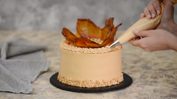 Закрыть женские руки украшая торт карамельным кремом . — стоковое видео