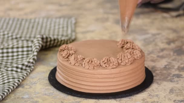 Baker versierde chocolade taart met room. — Stockvideo