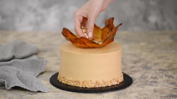 Konditor dekoriert den Karamellkuchen mit Erdnüssen. — Stockvideo