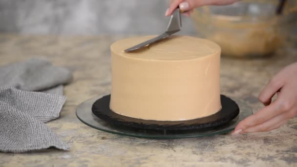 Aligner la crème au caramel avec une palette à pâtisserie sur un gâteau aux biscuits. Cuisson d'un gâteau au biscuit au caramel. Confiserie de maison . — Video