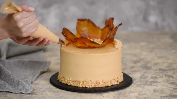 Fermer womans main décoration gâteau avec de la crème au caramel . — Video