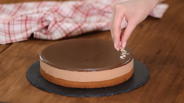 Kvinna dekorera och strö nötter på toppen choklad mousse kaka. — Stockvideo