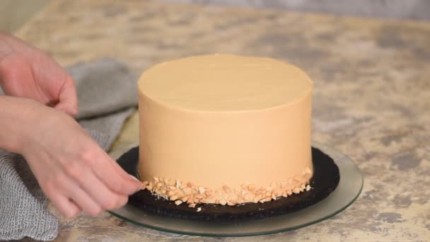 Cocinero pastelero decorando el pastel de caramelo con un maní . — Vídeo de stock