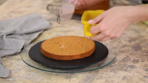 Mão de confeiteiro fêmea irreconhecível embebe bolo de esponja com xarope de caramelo doce usando escova de cozinha de silício na cozinha, close-up . — Vídeo de Stock