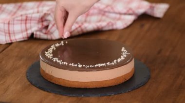 Çikolatalı kremalı pasta üzerine fındık serpiştiren bir kadın..