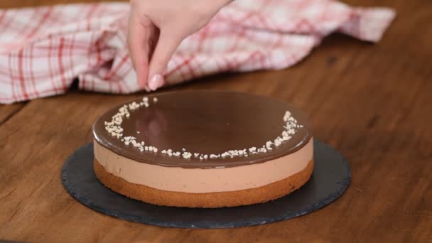 Nő díszítő és szórás dió tetején csokoládé mousse torta. — Stock videók