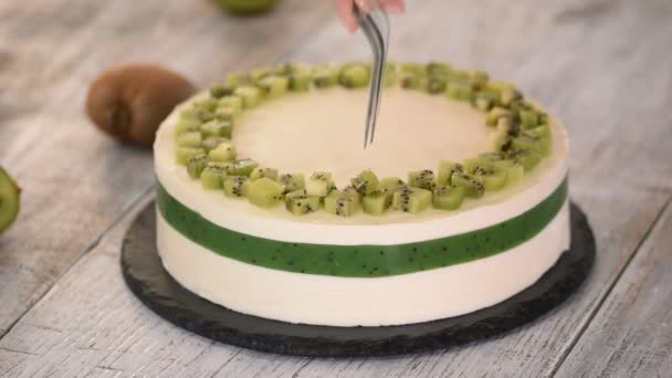 Chef-kok versieren de taart met verse kiwi. Zelfgemaakte mousse cake met kiwi. — Stockvideo