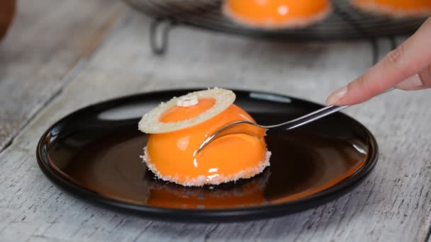 Manger un gâteau en mousse moderne avec glaçure miroir orange . — Video