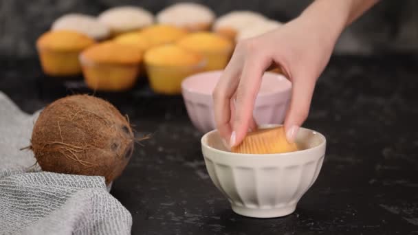 Muffins trempés femme dans le chocolat blanc liquide et flocons de noix de coco . — Video