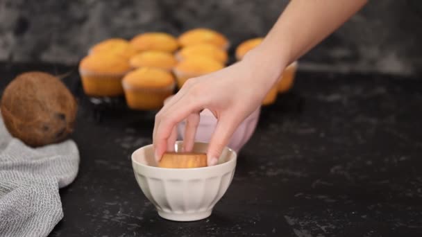 하얀 초콜릿 과 코코넛 조각에 머핀을 담근 여자. — 비디오