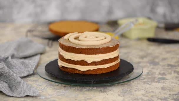 Una chica haciendo un pastel en una panadería. Baker aprieta crema sobre una capa de pastel . — Vídeos de Stock