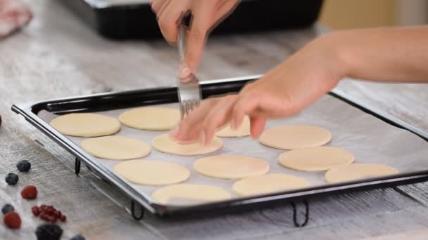 Vrouw piercet deeg in een ovenschaal met een vork. — Stockvideo