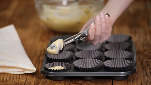 Hände gießen Teig in Formen für Muffins auf einem Holztisch. — Stockvideo