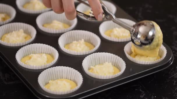 Het vullen van de papiermallen met deeg om muffins te maken. — Stockvideo