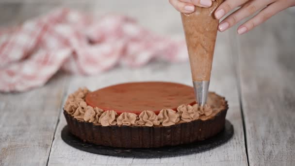 Confeiteiro decora deliciosa torta de chocolate com confit de cereja e creme de chocolate . — Vídeo de Stock
