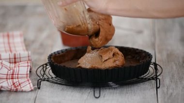 Pasta şefi badem kremalı çikolatalı pasta yapar. Çikolata hamurunu tart kalıbına döküyorum..
