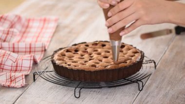 Şekerci çikolatalı kremayı bir pasta torbasından çikolatalı turtaya sıkıştırıyor..