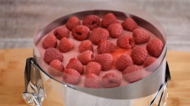 Pasta şefi ahududulu kekin üzerine kırmızı jöle döker..